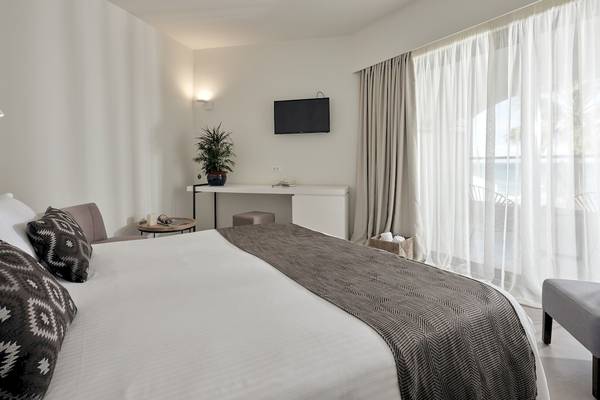 Innenansicht eines Zimmers im Caravel Hotel mit Bett, Dekor und Blick auf den Ozean.