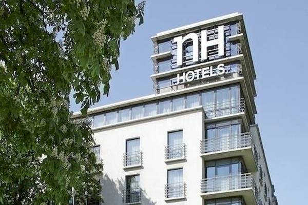 Außenansicht des NH Berlin Alexanderplatz Hotels mit grünen Bäumen und Berliner Fernsehturm.