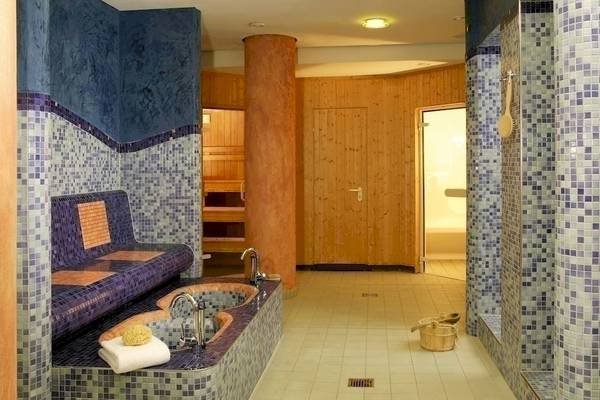 Saunabereich im NH Berlin Alexanderplatz Hotel mit gefliesten Wänden und einer Badewanne.