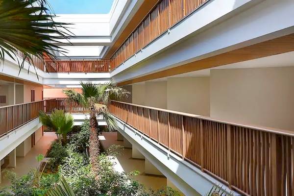 Innenhof des Hilton Cabo Verde Sal Resorts mit Holzbalkonen, Palmen und Pflanzen.
