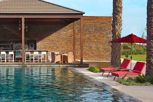 Poolbar des Hilton Cabo Verde Sal Resorts mit Lounge-Stuhl und Sonnenschirm.