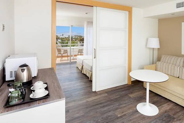 Innenansicht eines Zimmers im Sol Lanzarote All Inclusive Hotel mit einem kleinen Tisch, einer Couch und einem offenen Balkon.
