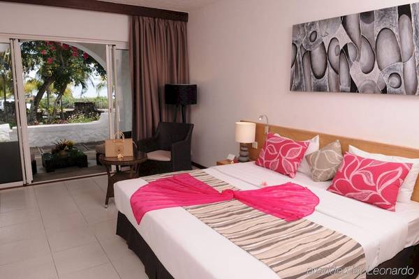 Hotelzimmer im Casuarina Resort & Spa mit einem Bett, Kissen, Lampen und einem Blick auf den Garten.