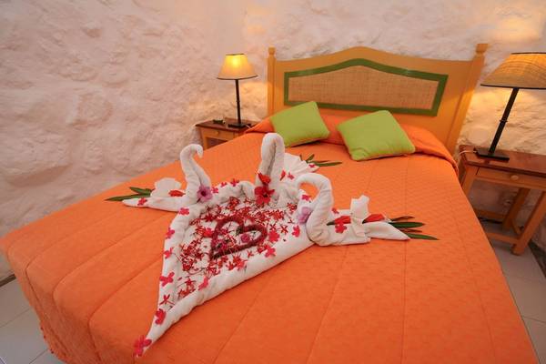 Hotelzimmer im Casuarina Resort & Spa mit orangem Bett und Blumendekoration.