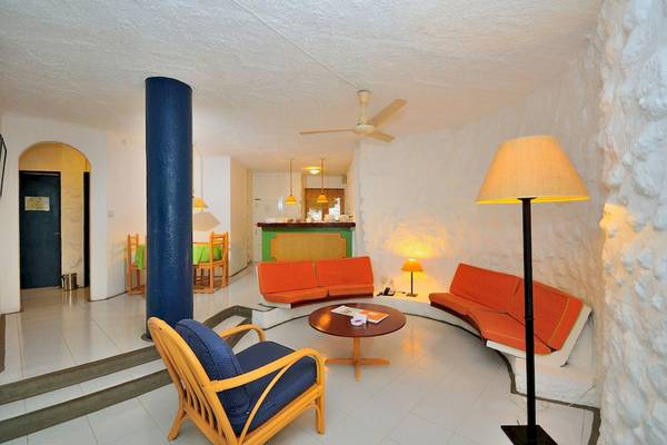 Innenbereich des Casuarina Resort & Spa mit weißen Wänden, orangefarbenen Sofas und einer grünen Tischplatte.