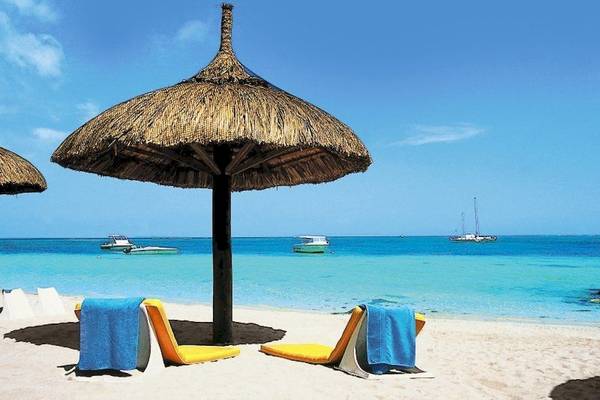 Strand des Casuarina Resorts mit Sonnenliegen und Sonnenschirmen am Meer