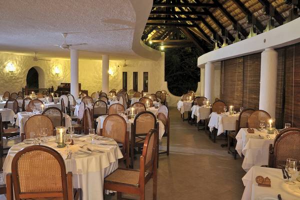 Innenansicht des Restaurants im Casuarina Resort & Spa mit gedeckten Tischen und Kerzen.