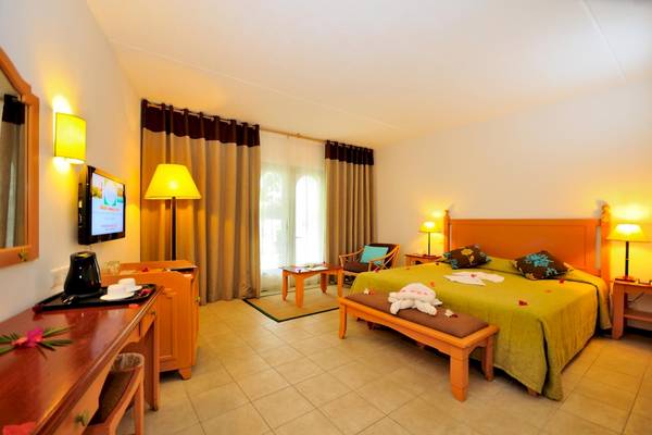 Innenansicht eines Hotelzimmers im Casuarina Resort & Spa mit Bett, Schreibtisch und Fernseher.