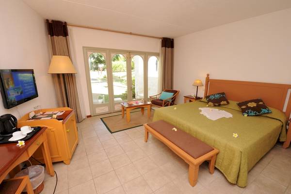Schlafzimmer im Casuarina Resort & Spa mit Doppelbett, Fernseher, Schreibtisch und Balkon.