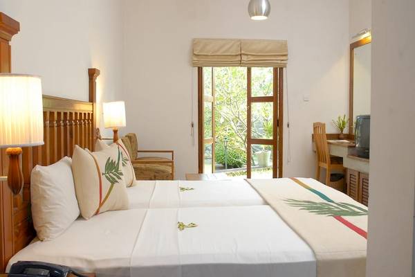 Schlafzimmer im Siddhalepa Ayurveda Health Resort mit zwei Betten, weißem Bettzeug, zwei Nachttischen und einem Telefon.