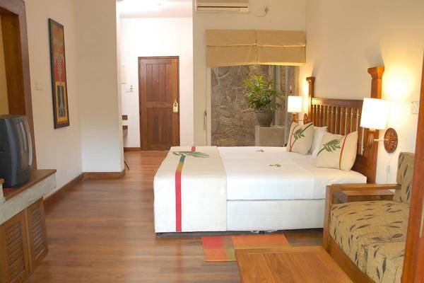 Innenansicht eines Schlafzimmers im Siddhalepa Ayurveda Gesundheitsresort mit Doppelbett, Kissen und Wanddekoration.
