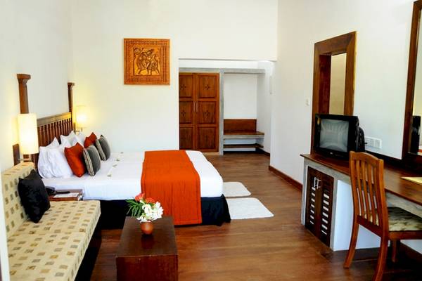 Ein modernes Hotelzimmer mit Bett, Couch, Schreibtisch und Fernseher.