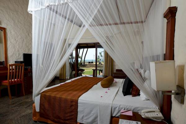 Ein Bett im Siddhalepa Ayurveda Gesundheitsresort mit einem Moskitonetz und einem Fernseher.