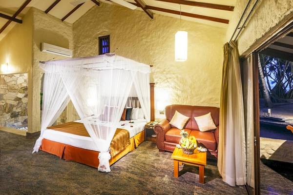 Schlafzimmer im Siddhalepa Ayurveda Health Resort mit Bett, Couch und Früchten.
