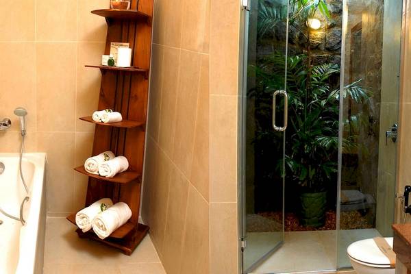 Badezimmer im Siddhalepa Ayurveda Gesundheitsresort mit Badewanne, Dusche, Toilette und Regal mit Handtüchern.