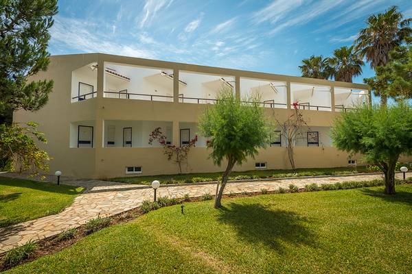 Außenansicht des Pavlina Beach Hotels mit mehreren Stockwerken, Balkonen und umliegender Grünfläche.