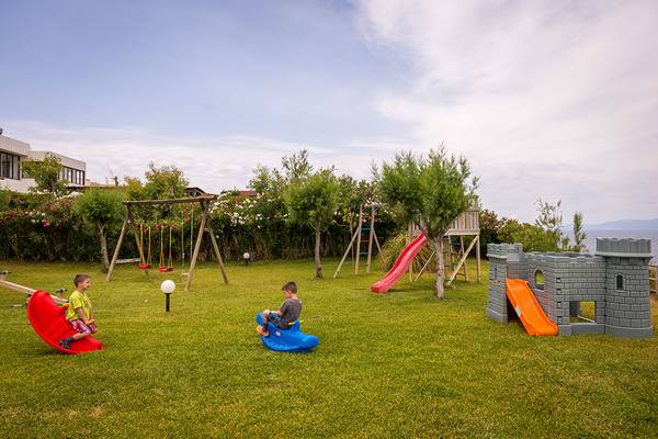 Zwei Kinder spielen auf einem Spielplatz im Freien im Pavlina Beach Hotel.