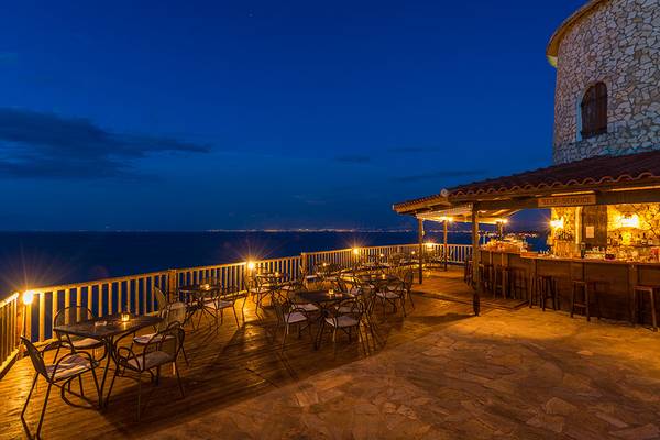 Abendansicht der Pavlina Beach Bar mit Blick auf das Meer und beleuchteten Tischen und Stühlen.