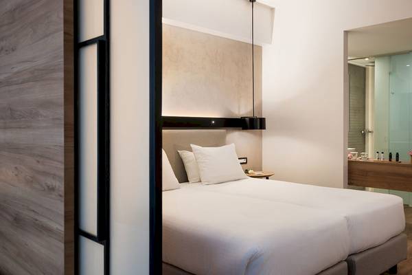 Schlafzimmer im Euphoria Resort mit zwei weißen Betten, weißen Kissen, einem Nachttisch und einer Holzwand.
