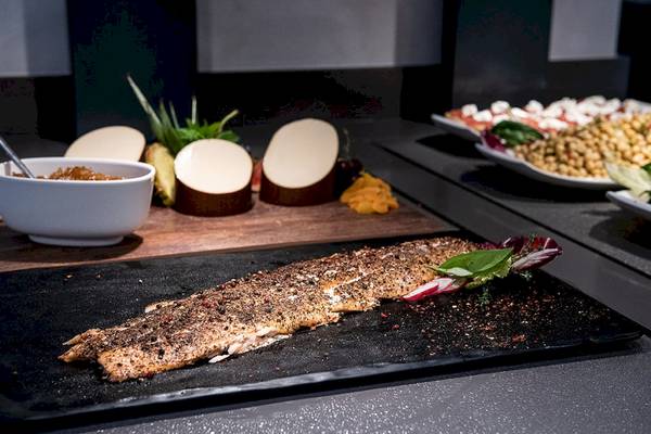 Gebratener Fisch auf einer schwarzen Platte im Euphoria Resort mit Beilagen.