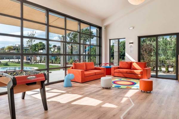 Kinderspielzimmer im Euphoria Resort mit orangenen Sofas, Tischkicker und buntem Teppich.