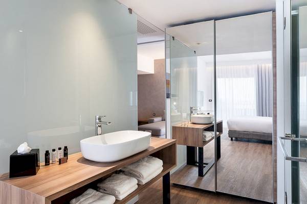 Badezimmer im Euphoria Resort Hotel mit Waschbecken, Handtüchern und Bett im Hintergrund.