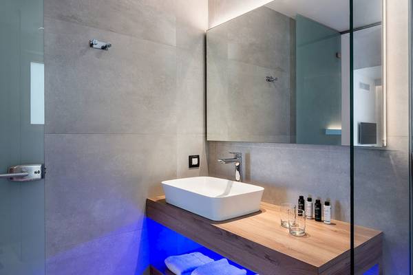 Badezimmer im Euphoria Resort mit grauen Fliesen, weißem Waschbecken und beleuchtetem Unterschrank.
