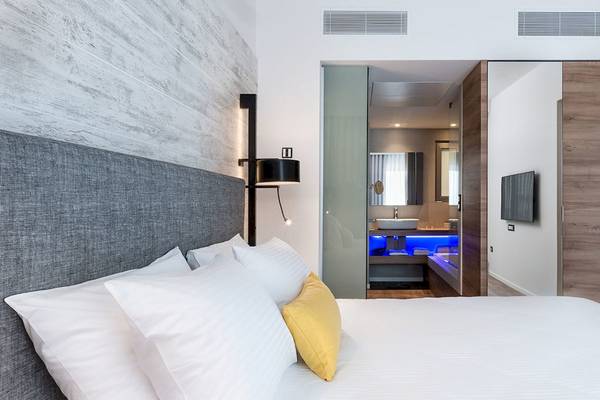Schlafzimmer im Euphoria Resort mit Bett, Kissen, Lampe und Badezimmeransicht.