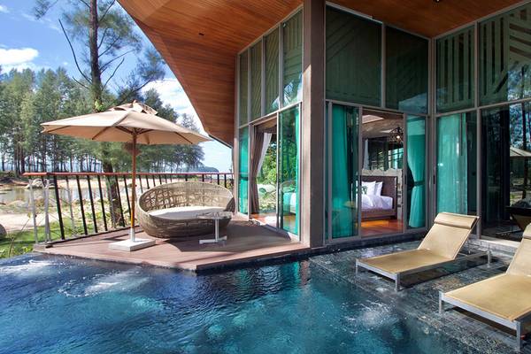 Außenbereich des Kalima Resort mit Swimmingpool, Sonnenliegen und einem Sonnenschirm neben einer Terrasse.