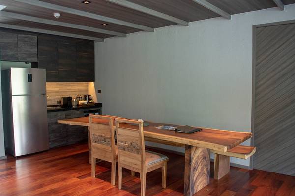 Esstisch in Holzdesign in einer Küche mit Kühlschrank und Kochfeld.