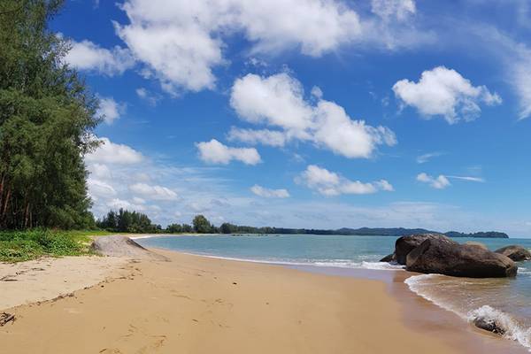 Strand des Kalima Resort & Villas Khao Lak mit Felsen und Bäumen