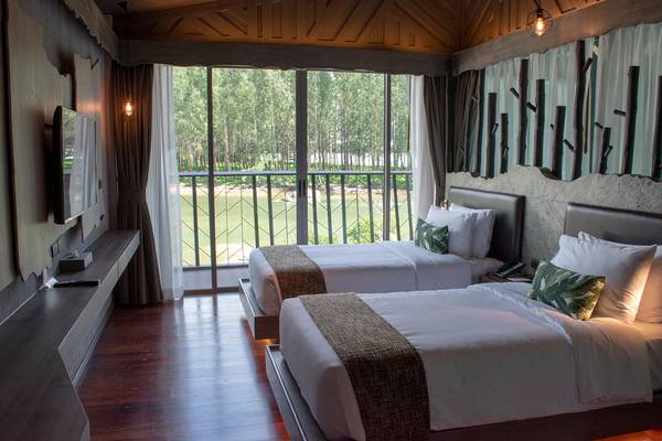 Ein Hotelzimmer im Kalima Resort & Villas Khao Lak mit zwei Betten, einem Fernseher und einer Aussicht auf ein Golfplatz.