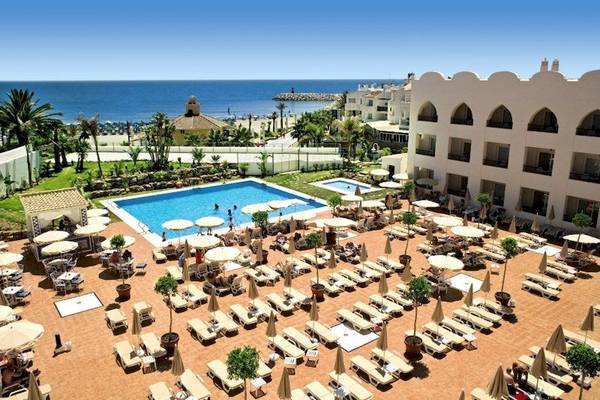 Luftaufnahme eines Resorts mit Swimmingpool, Sonnenliegen, Palmen und Meer im Hintergrund
