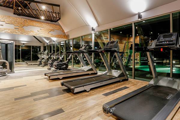 Fitness-Center im Kalima Resort & Villas Khao Lak mit mehreren Laufbändern und einem Pool im Hintergrund.