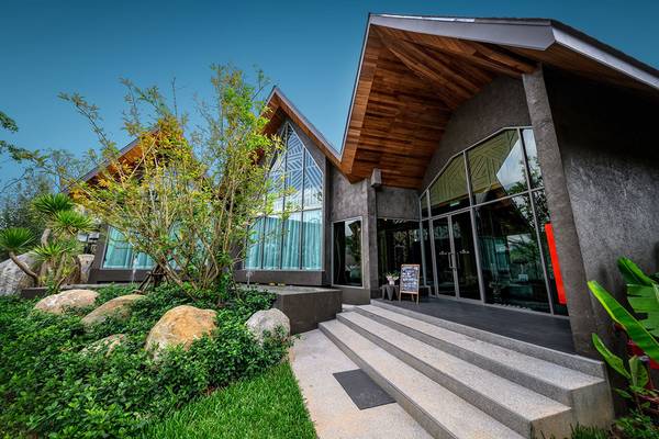 Außenansicht des Kalima Resort & Villas Khao Lak mit modernem Design, Glasfassade und Holzdach.