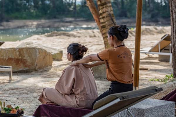 Eine Frau genießt eine Massage am Strand im Kalima Resort & Villas Khao Lak.