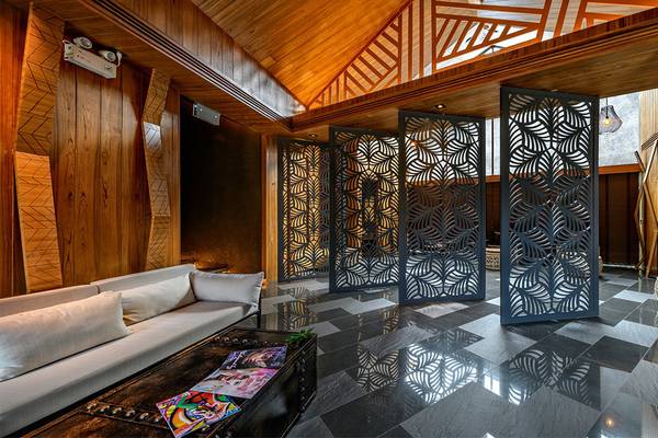 Innenraum des Kalima Resort & Villas Khao Lak mit geometrischen Trennwänden, einer weißen Couch und einem blauen Tisch.