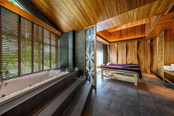 Holzgeprägtes Badezimmer im Kalima Resort & Villas Khao Lak mit Badewanne und Massageliege