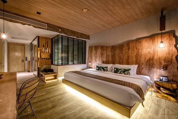 Innenansicht eines Zimmers im Kalima Resort & Villas Khao Lak mit Holzwänden, einem großen Bett und einem Fernseher.