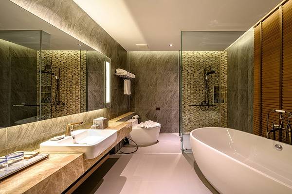 Kalima Resort & Villas Khao Lak Badezimmer mit Badewanne, Dusche, Waschbecken und Spiegel.