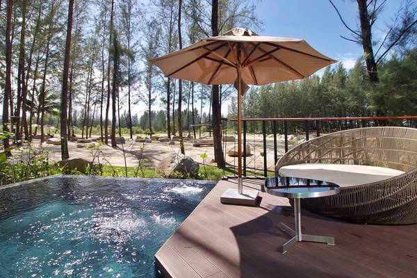 Außenbereich des Kalima Resort & Villas Khao Lak mit Pool, Sonnenschirm und Sitzecke.