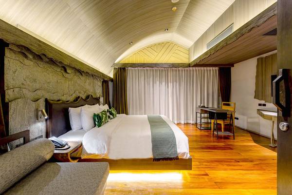 Ein modernes Schlafzimmer mit einem großen Bett, einem Schreibtisch und einem Sofa im Kalima Resort & Villas Khao Lak.
