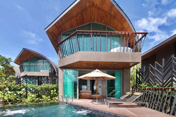Außenansicht des Kalima Resort & Villas Khao Lak mit Swimmingpool, Sonnenliegen und Sonnenschirm.