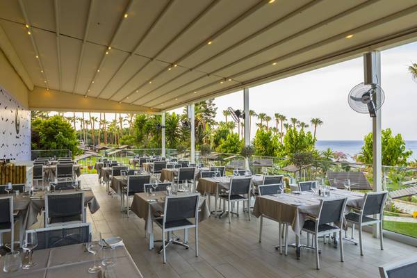 Außenterrasse des Cavo Maris Beach Hotels mit Blick auf das Meer.