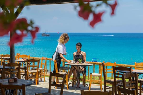 Zwei Frauen auf der Terrasse des Cavo Maris Beach Hotels mit Blick auf das Meer.