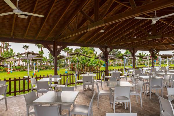 Außenterrasse des Cavo Maris Beach Hotels mit weißen Tischen und Stühlen