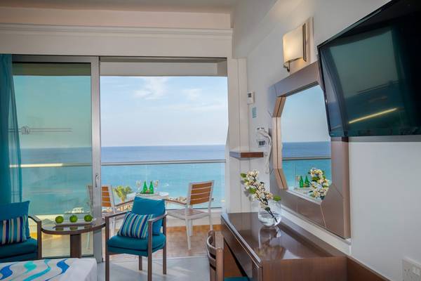 Zimmer mit Meerblick im Cavo Maris Beach Hotel mit Balkon, Schreibtisch, Fernseher und Meersicht.