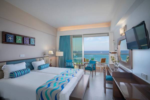 Doppelzimmer im Cavo Maris Beach Hotel mit Meerblick, zwei Betten und Balkon.