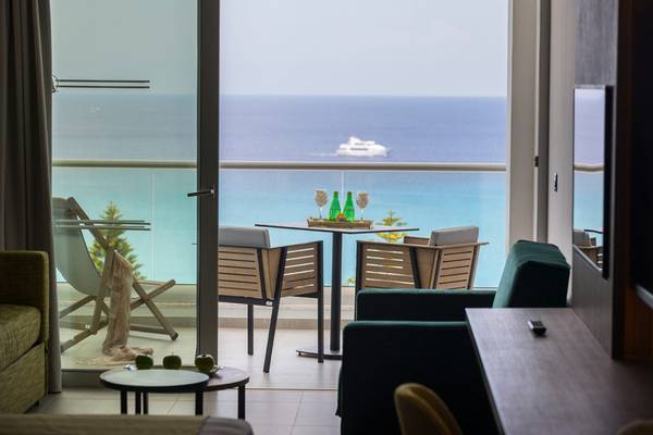Innenraum des Cavo Maris Beach Hotel Zimmers mit Terrasse und Aussicht auf das Meer.