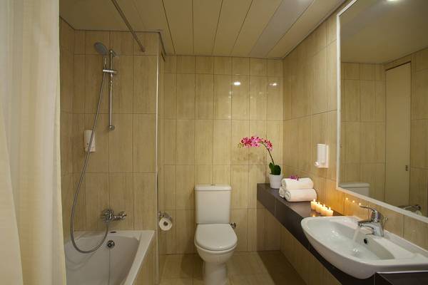 Badezimmer im Queens Bay Hotel mit Badewanne, Toilette, Waschbecken und Spiegel.